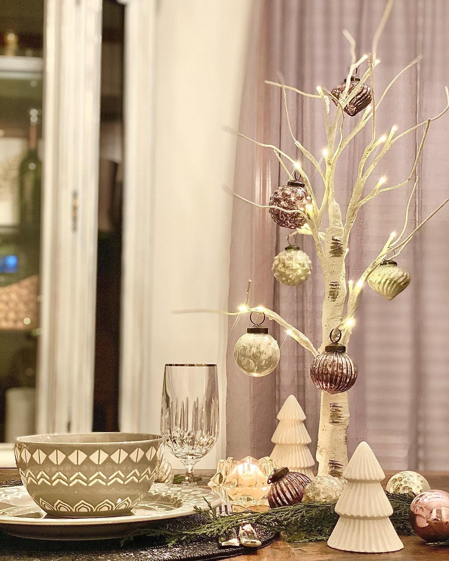 Holiday table with a lit birch tree and mercury glass ornaments